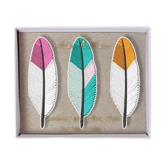 three different colored feathers in a box