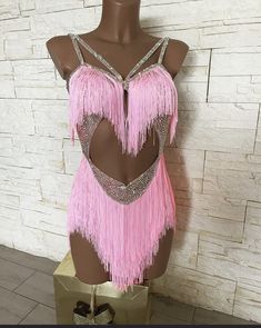 a mannequin with pink fringe on it's chest and back in front of a white brick wall