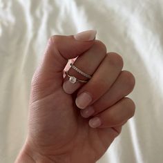 a woman's hand holding a diamond ring on top of her left hand,