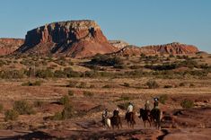 three people are riding horses in the desert