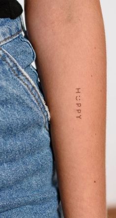 a woman's arm with the word happy tattooed on her left arm, in black ink