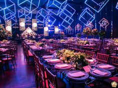 a large banquet hall with tables and chairs set up for an event or function, lit by colorful lights