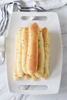 a white plate topped with four hot dogs on top of buns next to a black and white towel