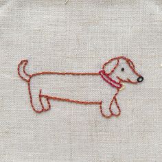 a small embroidered dog on a piece of linen with orange thread and red stitching