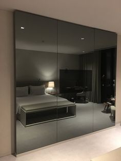 a bedroom with mirrored walls and a bed in the middle is seen from across the room