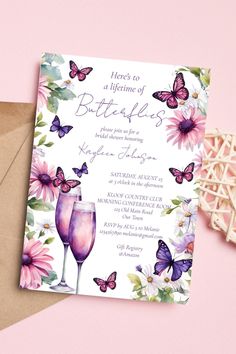 there is a card with butterflies on it and two wine glasses in front of the card