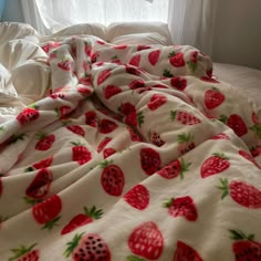 an unmade bed with strawberry print on it