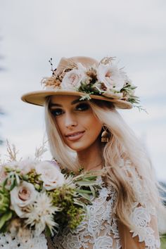 a woman with long blonde hair wearing a hat and holding flowers