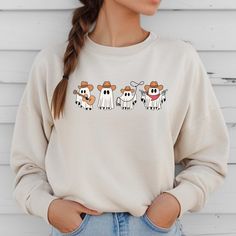 Stay cozy and stylish in our Cowboy Ghosts Sweatshirt. This western-inspired sweater features cute ghost designs that will add a playful touch to your wardrobe. Get ready to turn heads and keep warm in our unique and fun sweatshirt. Trendy Fall Sweatshirt With Character Print, Trendy Character Print Sweatshirt For Fall, White Fun Sweater For Fall, Fun White Sweater For Fall, Casual Fall Sweatshirt With Cartoon Print, Casual Fall Cartoon Print Sweatshirt, White Cartoon Print Sweater For Fall, Fall Cartoon Print Tops For Loungewear, Fun Fall Loungewear Tops