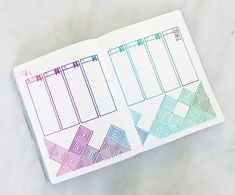 an open planner book with colorful lines on the pages and numbers in each section, sitting on top of a marble surface