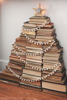 a christmas tree made out of books with lights on it and a star above the top