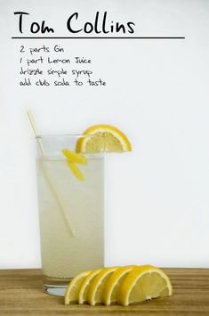 a tall glass filled with lemonade on top of a wooden table next to sliced lemons