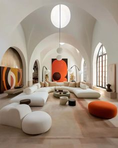 a large living room with lots of white couches and orange accents on the walls