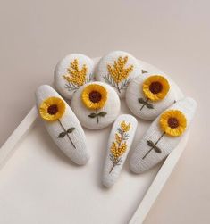 six sunflowers are placed on top of a white tray with yellow flowers in the middle