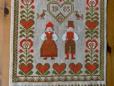 a cross - stitched mat with two people holding hands and hearts on the ground