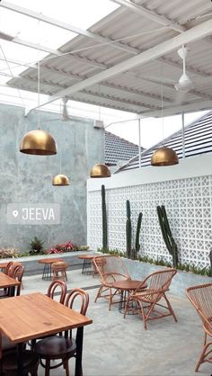 an outdoor dining area with wooden tables and chairs in front of a wall that says jeeva