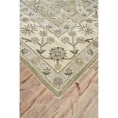 a beige and green rug on top of a wooden floor