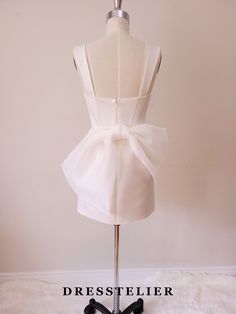 a white dress on a mannequin with a bow at the waist and back