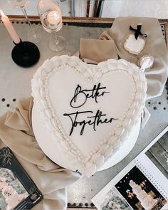 a heart - shaped cake with the words better together written on it, surrounded by photos and candles