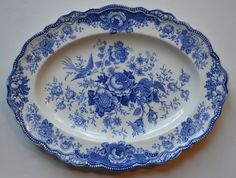 a blue and white platter with flowers on the rim is sitting on a table