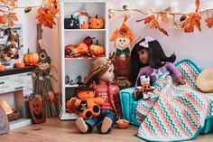 two dolls are sitting on the floor in front of pumpkins and other halloween decorations