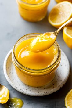 a spoon full of orange custard on top of a plate with sliced lemons