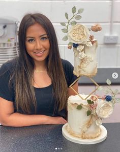 a woman standing next to a three tiered cake on top of a black counter