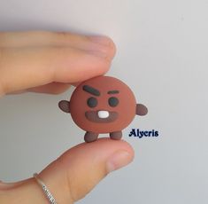 a hand holding a small brown toy with eyes and nose on it's finger