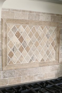 a tile backsplash in a kitchen with an oven and stove top underneath it