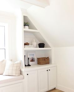 a room with white walls and wooden flooring, built - in bookshelves