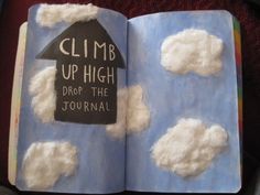 an open book with clouds and a chalkboard on the cover that says climb up high, drop the journal