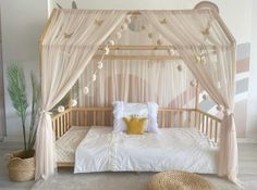 a bed with a canopy and pillows on it in a room that has white walls