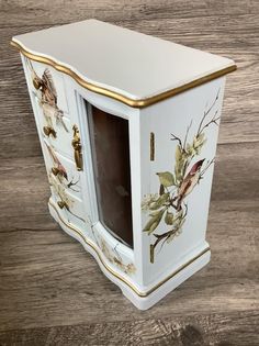 a white and gold painted cabinet with flowers on it