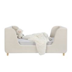 a small child's bed with a teddy bear on it and a white blanket