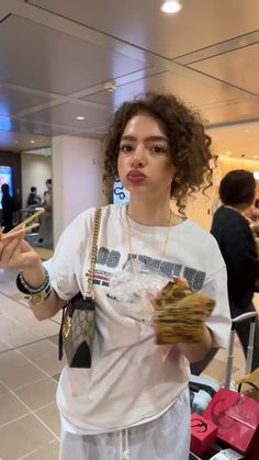 a woman is standing in an airport with her hand out to the side and holding something