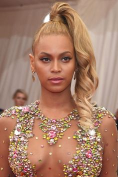 a woman with blonde hair wearing a flowered dress and statement earrings on the red carpet