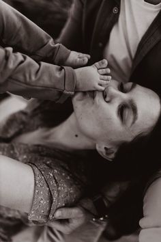 a black and white photo of a woman holding a baby's hand over her head