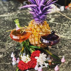 a pineapple sitting on top of a table next to flowers