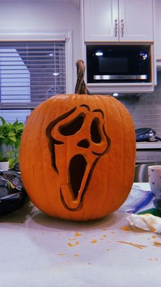 a carved pumpkin with a ghost face on it's side and mouth open in front of a kitchen counter