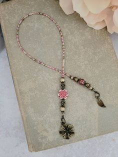 a pink and black beaded lanyard with a flower on it next to flowers