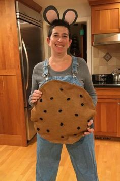 a woman holding up a cookie shaped like a mouse