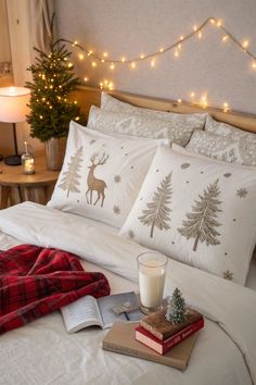 a bed topped with pillows and blankets next to a night stand filled with christmas lights