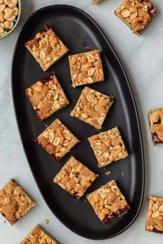 a black plate topped with brownies and nuts