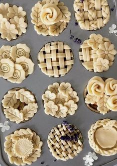 twelve pies are arranged in the shape of flowers on a baking tray with lavender sprigs