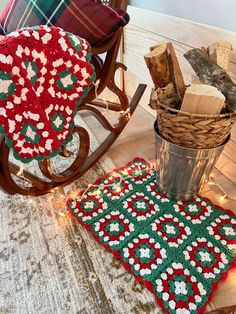 a wooden rocking chair next to a crocheted christmas rug and pot holder on the floor