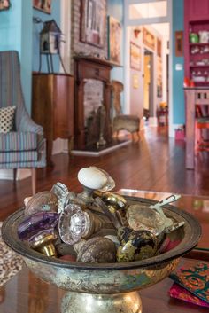 a bowl filled with lots of clutter sitting on top of a wooden floor next to a chair