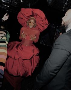 a woman in a red dress standing next to two men