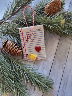 an ornament hanging from a pine tree with writing paper and candy canes