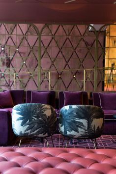 two purple chairs sitting next to each other in front of a wall with decorative panels