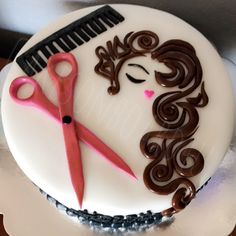 a white cake decorated with hair and scissors